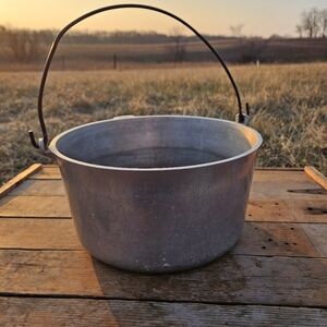 vintage cast aluminum cooking pot or kettle with a bail handle.